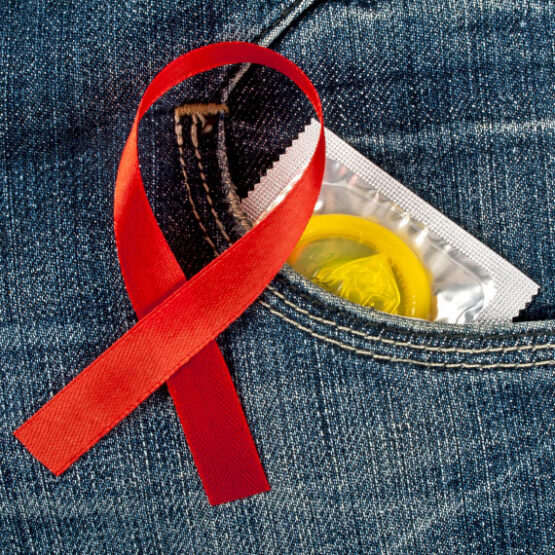 Nahaufnahme (Symbolbild): AIDS-Schleife und verpacktes Kondom.